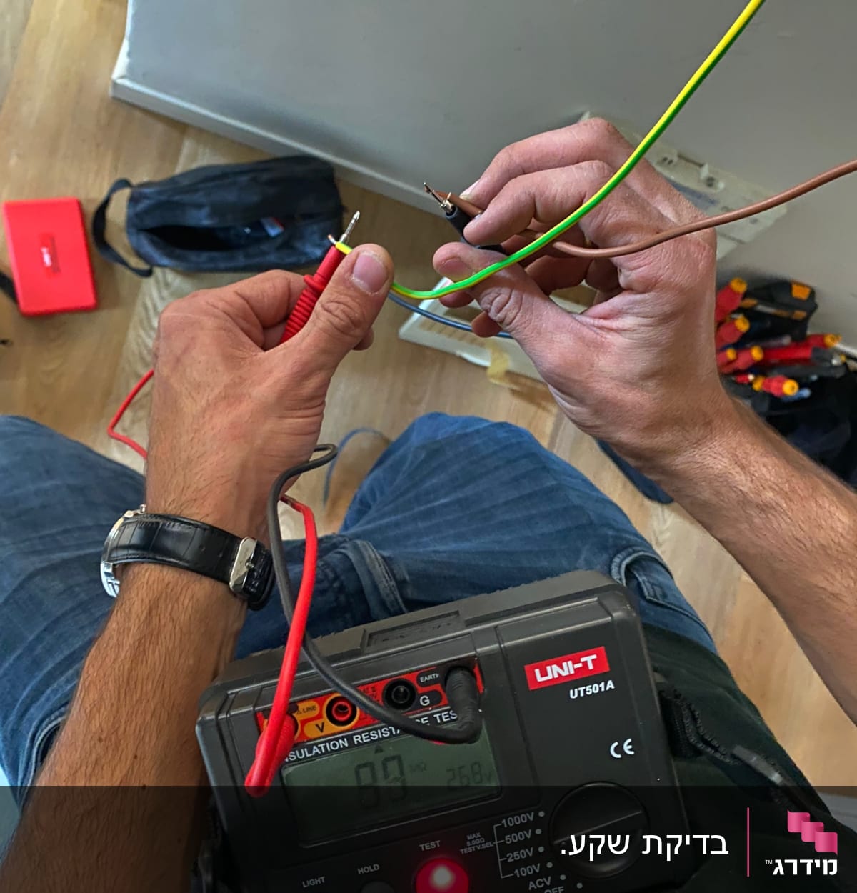 חשמלאי בודק חוטים עם מד מתח בידיו